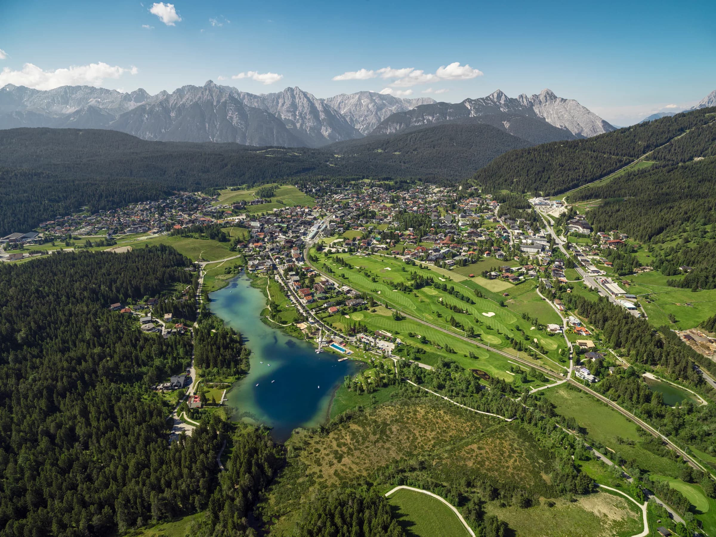 Drohnenaufnahme des Wildsees in Seefeld mit dem Golfplatz im Vordergrund und dem Karwendelgebirge dahinter